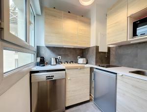 a kitchen with stainless steel appliances and wooden cabinets at Appartement centre Orsay in Orsay +4 photos
