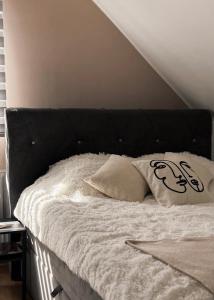 a bed with a black headboard and two pillows on it at Apartman Ilić in Divčibare
