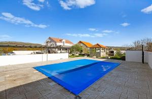 ein blauer Swimmingpool in einem Garten mit einem Haus in der Unterkunft Vila Zagora in Drniš