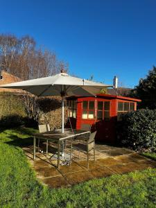 una mesa y una sombrilla frente a una casa en Big Group Bungalow, Sleeps 9, Perfect for Families, en Sturminster Newton