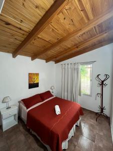 a bedroom with a red bed and a wooden ceiling at Cabaña brisas del lago in Villa Parque Siquiman