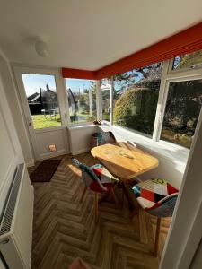 Una habitación con una mesa y sillas y ventanas. en Big Group Bungalow, Sleeps 9, Perfect for Families, en Sturminster Newton