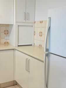 een keuken met witte kasten en een koelkast bij 2Bdr Beachfront Apartment - First Bay Coolum in Coolum Beach
