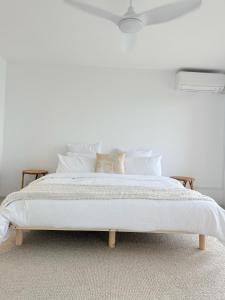 een wit bed met witte lakens en kussens bij 2Bdr Beachfront Apartment - First Bay Coolum in Coolum Beach