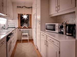 a kitchen with white cabinets and a microwave at Aurora House in Karungi