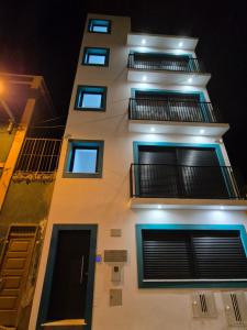 a tall white building with blue windows at night at Casa Morada in Mindelo