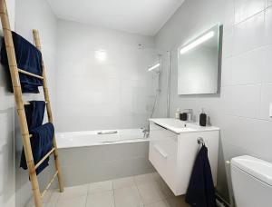 a white bathroom with a sink and a bath tub at Appartement centre Orsay in Orsay