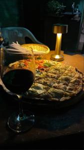 a pizza on a table with a glass of wine at Green Lodge Eco Life Hotel in Florianópolis