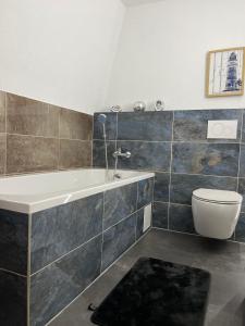 a bathroom with a bath tub and a toilet at Riverside-Appartements in Boppard +42 photos