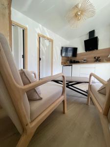 een woonkamer met een stoel en een tv bij Caprice Gruissanais Suite avec Spa privatif in Gruissan