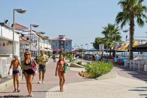 a group of people walking down a sidewalk near the beach at Lea's Apartment in Kourouta