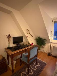 a desk with a computer and a chair in a room at Cosy room in attic flat in the center of Zurich in Zürich