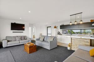 Una sala de estar con dos sofás y una cocina. en Seabreeze Lookout - Moeraki Holiday Home, en Moeraki