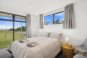 Un dormitorio con una cama y una ventana grande. en Seabreeze Lookout - Moeraki Holiday Home, en Moeraki