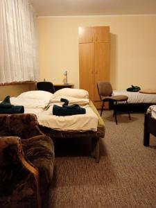 een kamer met drie bedden en stoelen in een kamer bij Hotel Sowa in Częstochowa +5 foto's