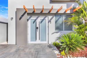 Una casa blanca con una puerta blanca y algunas plantas. en AQUA Ville Moderna - Serene 16BR Coastal Haven Villa with Pool, en Dorado