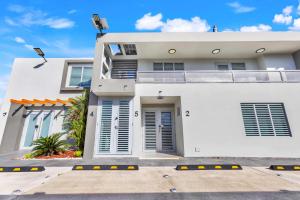 una casa blanca con una entrada delante de ella en AQUA Ville Moderna - Serene 16BR Coastal Haven Villa with Pool, en Dorado