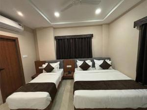 a hotel room with two beds and a window at Hotel Pragya Paradise in Indore
