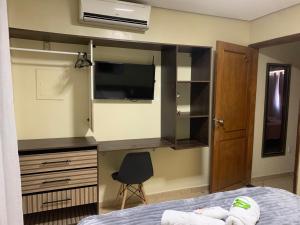 a bedroom with a bed and a desk with a television at Apto 013 - Residencial Canaã in Porto Velho