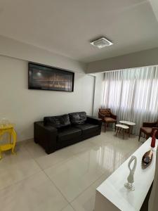 a living room with a black couch and a tv at Ap inteiro St Bueno 2 quartos in Goiânia
