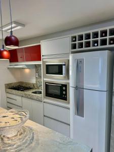a kitchen with a white refrigerator and a microwave at Ap inteiro St Bueno 2 quartos in Goiânia