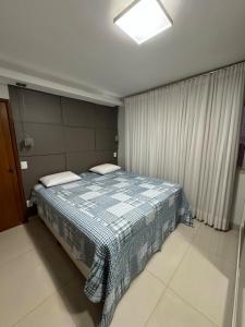 a bedroom with a bed with a blue and white blanket at Ap inteiro St Bueno 2 quartos in Goiânia