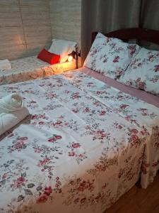 un letto con una coperta bianca con fiori rossi sopra di Casa reformada com Ar condicionado e Garagem, perto CMPC e BR 116 com Self Check-in a Guaíba