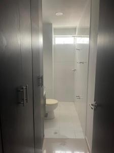 a bathroom with a toilet and a glass shower at Apartaestudio La Castellana in Montería