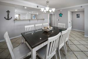una sala da pranzo con tavolo nero e sedie bianche di Surf Dweller 112 Large gulf front condo a Fort Walton Beach