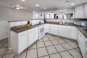 una cucina con armadi bianchi e ripiani in marmo di Surf Dweller 112 Large gulf front condo a Fort Walton Beach