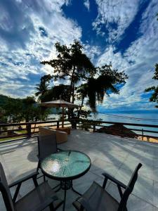 a patio with a table and chairs and the ocean at Espaço Villa Ará in Praia de Araçatiba