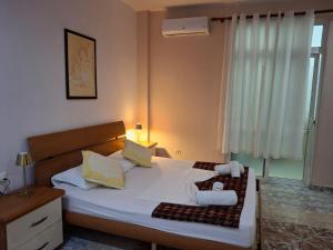 a bedroom with a bed with white sheets and a window at Chicago hotel in Fier +139 photos