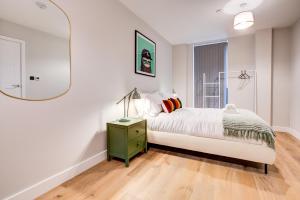 ein Schlafzimmer mit einem Bett mit einer Lampe und einem Spiegel in der Unterkunft Amity Moonbirds by Artsy in Raynes Park