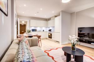 ein Wohnzimmer mit Sofa und eine Küche in der Unterkunft Amity Moonbirds by Artsy in Raynes Park