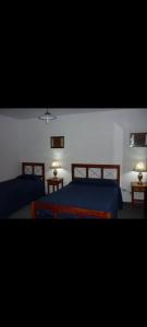 a bedroom with two beds with blue sheets and two lamps at Kilometro Cero in La Quiaca