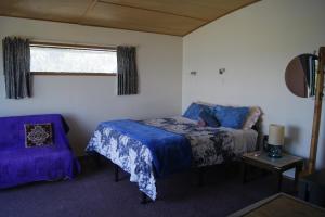 a bedroom with a bed and a chair and a window at Ocean Purring Views in Tutukaka