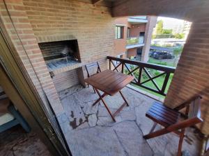 een patio met een bakstenen open haard en een houten tafel en stoel bij Club carilo playa Edificio del bosque in Carilo