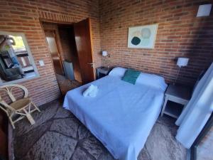 een slaapkamer met een bed en een bakstenen muur bij Club carilo playa Edificio del bosque in Carilo