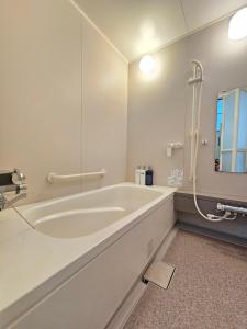 un bagno bianco con una grande vasca e uno specchio di furano lavender house a Furano