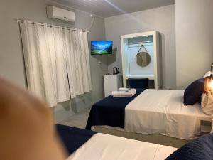 een kamer met 2 bedden en een tv. bij 101-Quarto Pousada Hg in Vila Nova do Sul