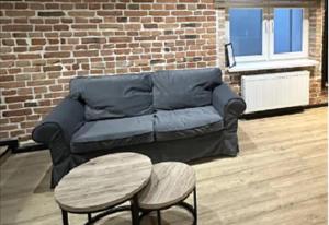 a couch and tables in a room with a brick wall at Warszawska in Toruń