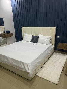 a large bed with white sheets and pillows at Serenity by Feliho House in Dakar