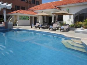 a swimming pool with chairs and umbrellas next to a house at Hotel Baluarte in Veracruz