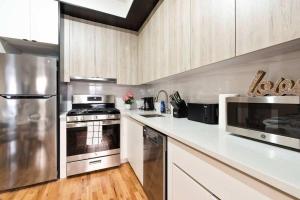 una cocina con encimeras blancas y electrodomésticos de acero inoxidable en Luxury 3BR Duplex w Private Patio in Upper East, en Nueva York