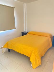 1 dormitorio con 1 cama con manta amarilla en Apart La Bella, en Chilecito