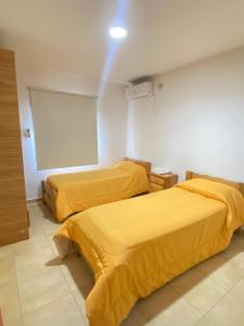 2 camas en una habitación con sábanas amarillas en Apart La Bella, en Chilecito