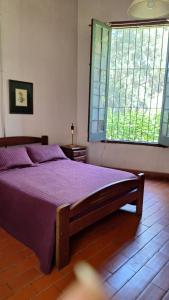 a bedroom with a bed with purple sheets and windows at Chacra del Molino in Navarro +41 photos