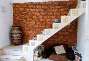 a white staircase in front of a brick wall with books at Casa de Adobe in Lençóis