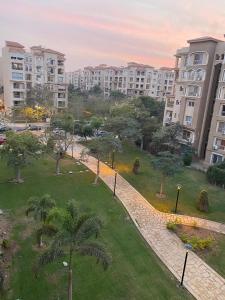 a park in the middle of a city with tall buildings at Central Park hotel apartment in Madinaty