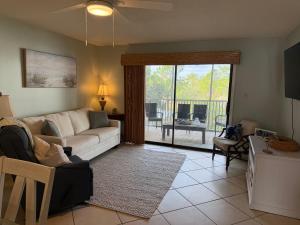 a living room with a couch and a table and a balcony at Latitude 107 2 bedroom walk to beach in Orange Beach
